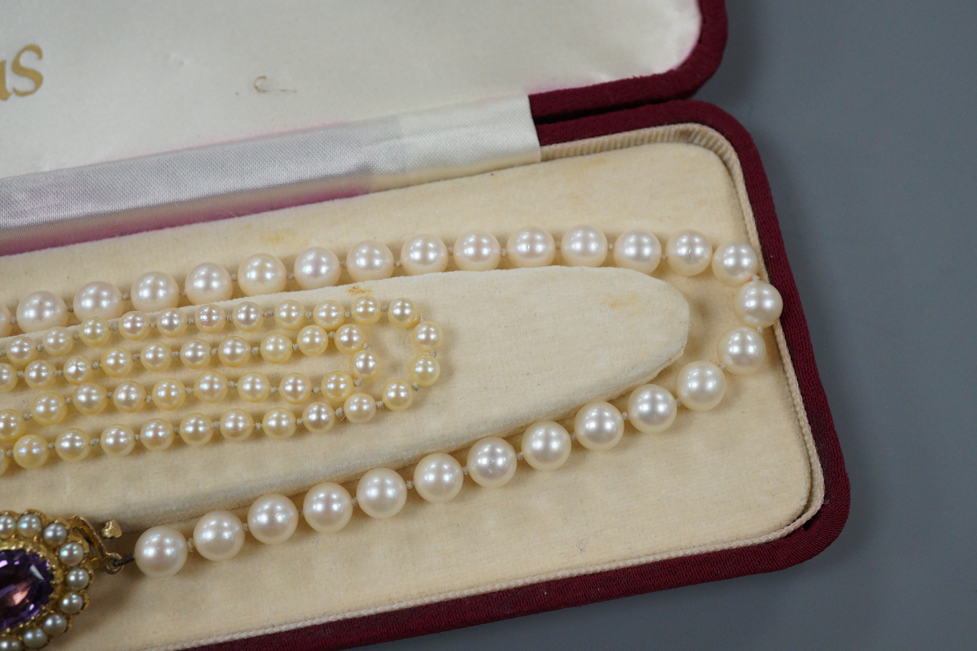 A modern single strand cultured pearl necklace, with 9ct, amethyst and cultured pearl set ova clasp, 44cm and one other single strand graduated cultured pearl necklace, with diamond chi set 9ct white gold clasp, 50cm.